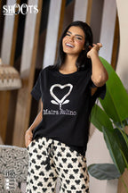 Woman wearing a black t-shirt with a white heart design and text, standing indoors.